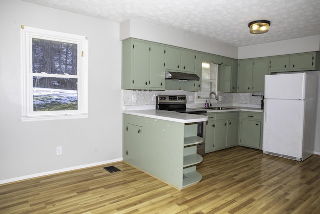 kitchen featuring stainless steel electric stove, white fridge, and green cabinets