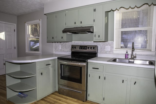 kitchen featuring sink, stainless steel electric range, light wood-type flooring, kitchen peninsula, and decorative backsplash