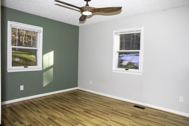 unfurnished room with ceiling fan, plenty of natural light, wood-type flooring, and a textured ceiling