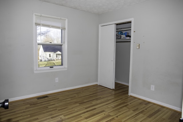 unfurnished bedroom with dark wood-type flooring, a closet, and a textured ceiling