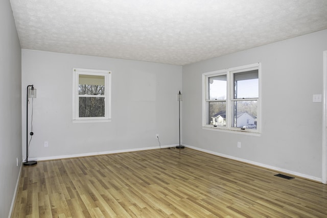 spare room with a textured ceiling and light wood-type flooring