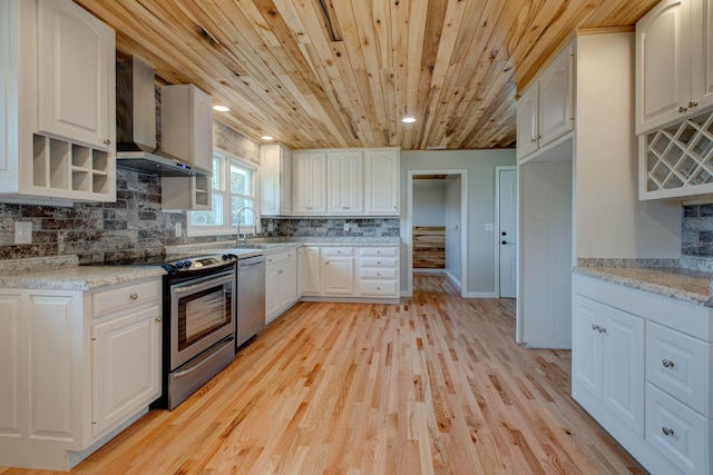 kitchen featuring white cabinetry, wall chimney exhaust hood, stainless steel appliances, and light stone countertops