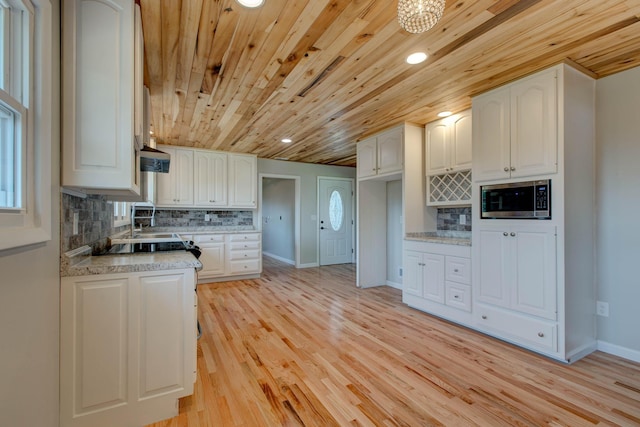 kitchen with wood ceiling, white cabinetry, stainless steel microwave, decorative backsplash, and light wood-type flooring