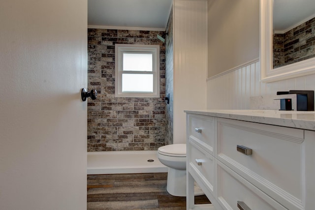 bathroom featuring vanity, hardwood / wood-style floors, toilet, and a tile shower