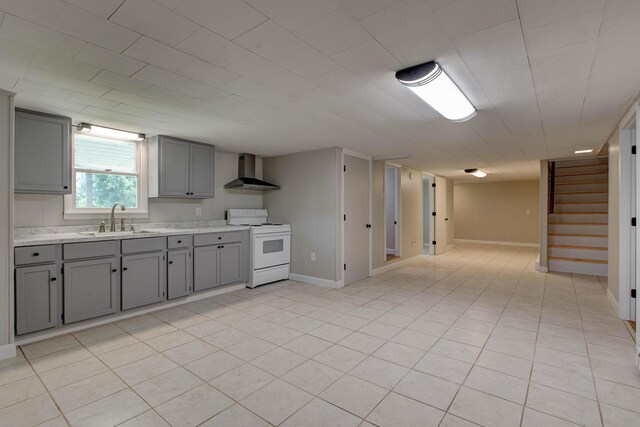 kitchen with electric stove, wall chimney range hood, sink, gray cabinets, and light tile patterned flooring