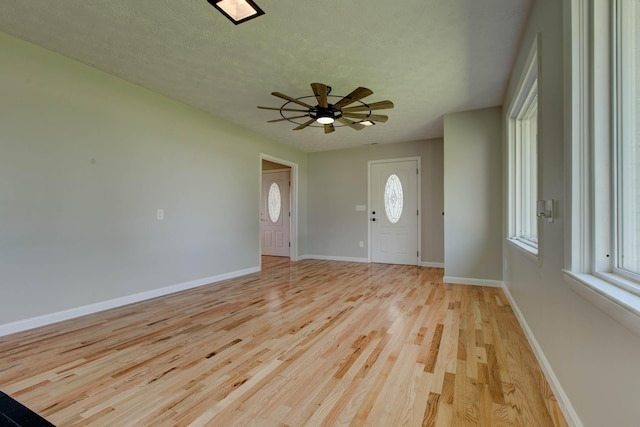 foyer entrance featuring ceiling fan, light hardwood / wood-style floors, and a textured ceiling