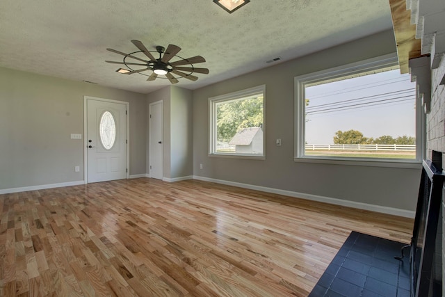 entryway with ceiling fan, a healthy amount of sunlight, a textured ceiling, and light hardwood / wood-style floors