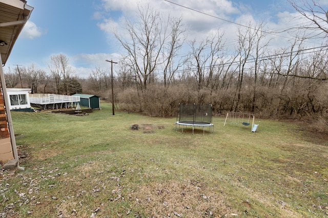 view of yard featuring a playground, an outdoor structure, and a trampoline