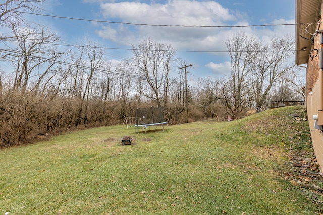 view of yard with a trampoline and a fire pit