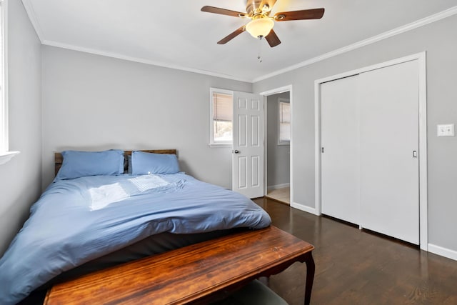 bedroom featuring dark wood-type flooring, ceiling fan, crown molding, and a closet