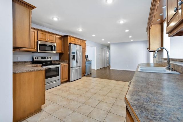 kitchen featuring stainless steel appliances, sink, and light tile patterned floors