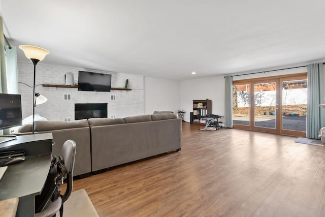 living room with a brick fireplace, hardwood / wood-style flooring, and brick wall