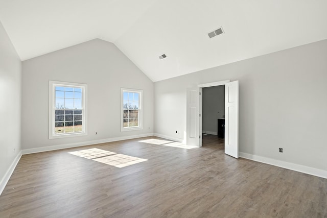 unfurnished room with hardwood / wood-style flooring and high vaulted ceiling