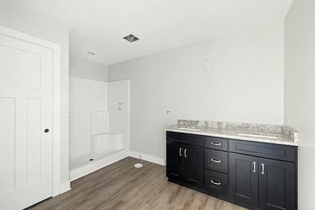 bathroom featuring wood-type flooring, vanity, and walk in shower