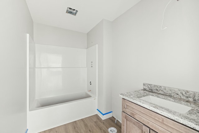 bathroom featuring vanity, wood-type flooring, and shower / washtub combination