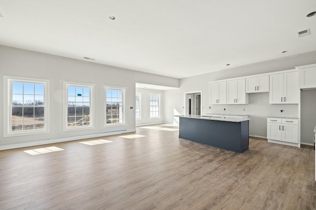 kitchen featuring light hardwood / wood-style floors, white cabinets, and a center island with sink