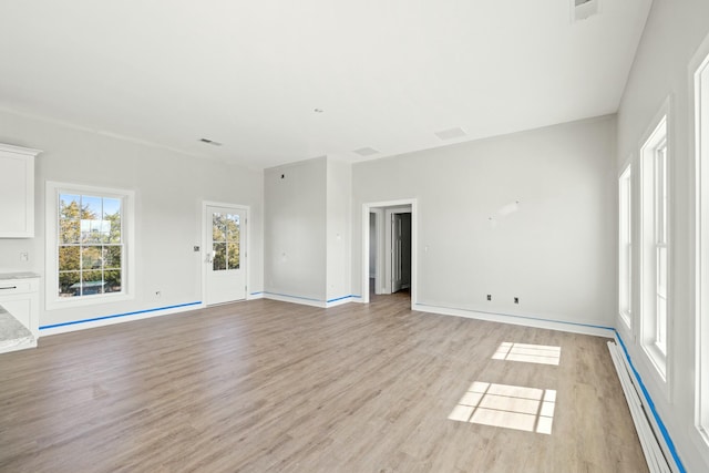 unfurnished living room with light hardwood / wood-style floors and baseboard heating