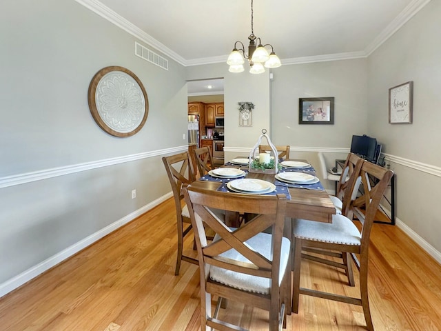 dining area featuring ornamental molding, light hardwood / wood-style floors, and a notable chandelier