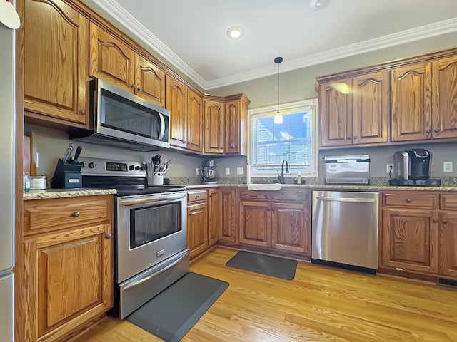 kitchen with sink, ornamental molding, light stone counters, stainless steel appliances, and light hardwood / wood-style flooring