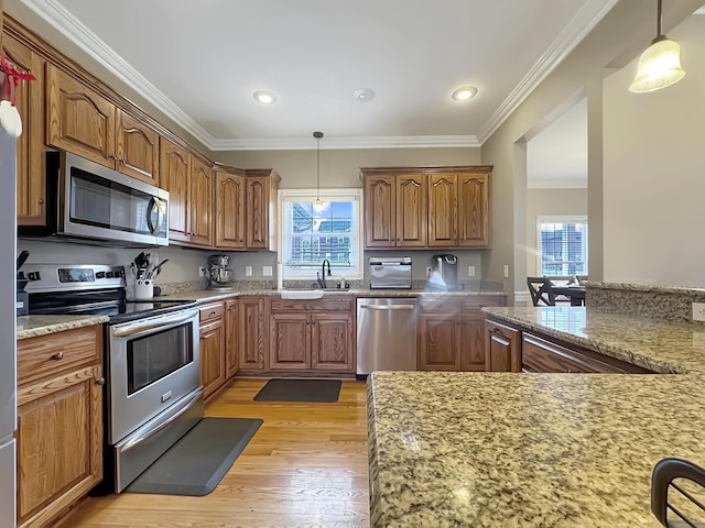 kitchen with crown molding, appliances with stainless steel finishes, pendant lighting, and light hardwood / wood-style flooring