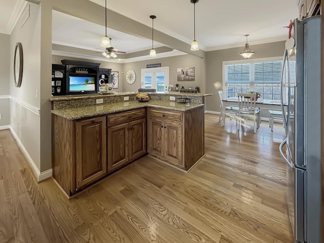 kitchen featuring stone counters, ornamental molding, hardwood / wood-style floors, and stainless steel refrigerator