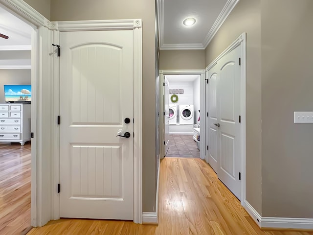 hallway with crown molding, washing machine and clothes dryer, and light hardwood / wood-style floors