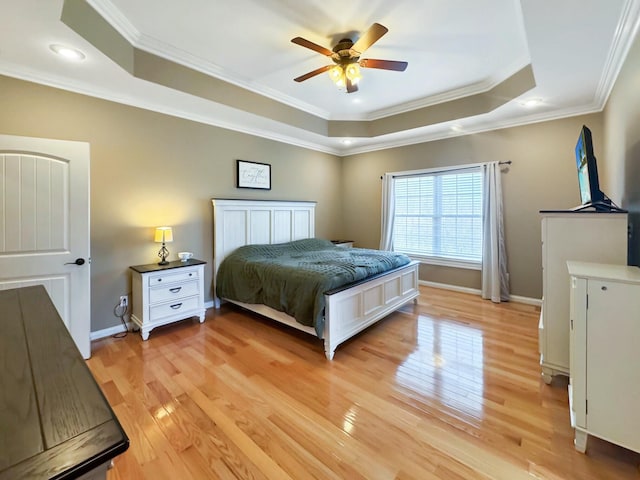 bedroom with a tray ceiling, ornamental molding, ceiling fan, and light wood-type flooring