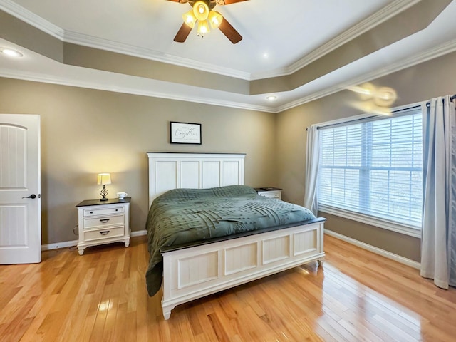 bedroom featuring a raised ceiling, crown molding, ceiling fan, and light hardwood / wood-style floors