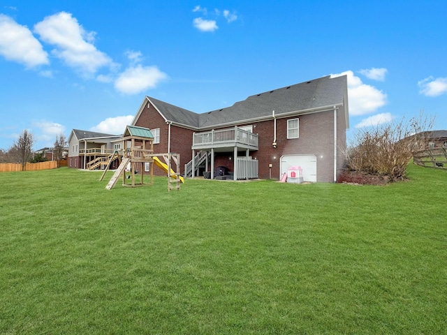 rear view of house featuring a garage, a playground, a deck, and a lawn