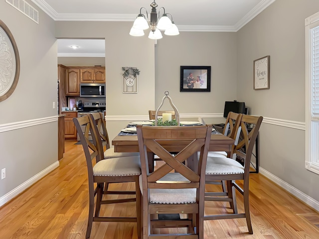 dining room with an inviting chandelier, crown molding, and light hardwood / wood-style flooring