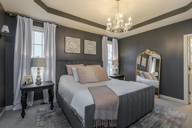 bedroom with a chandelier, dark carpet, and a tray ceiling