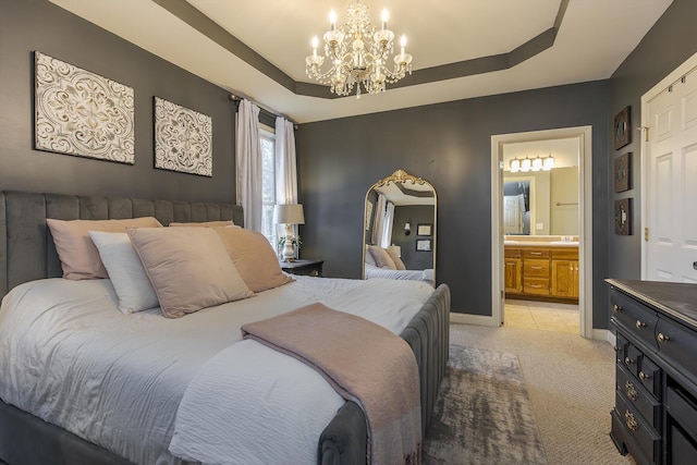 carpeted bedroom featuring a raised ceiling, connected bathroom, and a chandelier