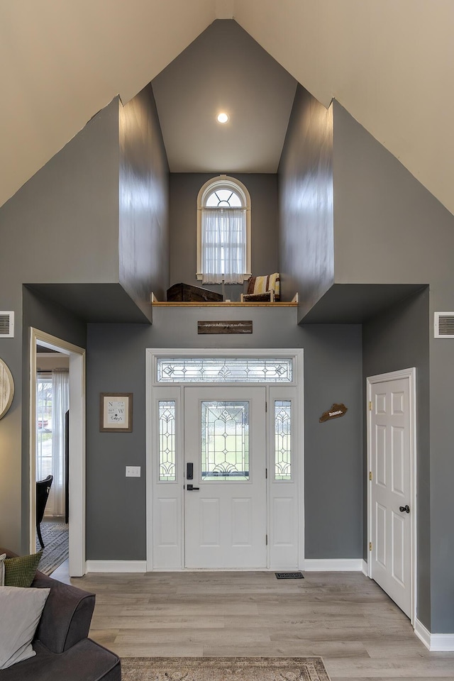 foyer with high vaulted ceiling and light hardwood / wood-style flooring