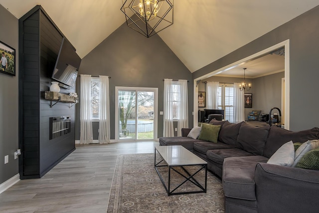 living room with an inviting chandelier, light hardwood / wood-style flooring, and high vaulted ceiling