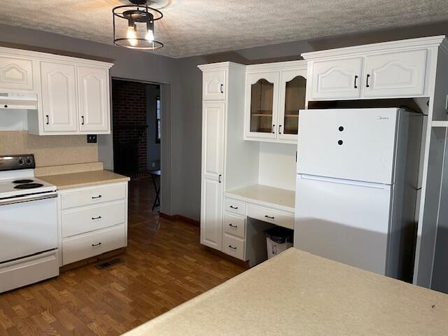 kitchen featuring white cabinetry, dark hardwood / wood-style flooring, a textured ceiling, and white appliances