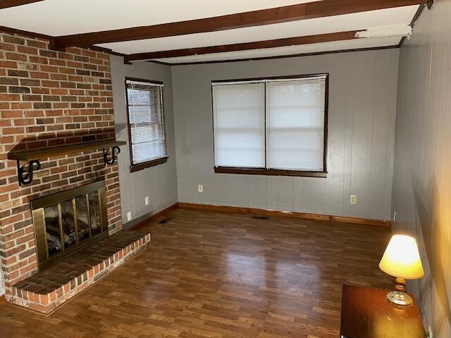 unfurnished living room featuring beamed ceiling, a fireplace, and dark hardwood / wood-style flooring