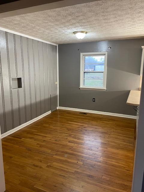 spare room featuring dark wood-type flooring and a textured ceiling