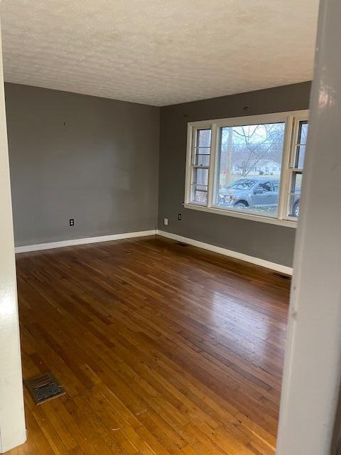 spare room featuring dark wood-type flooring and a textured ceiling