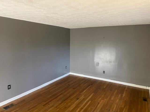 unfurnished room featuring dark hardwood / wood-style floors and a textured ceiling