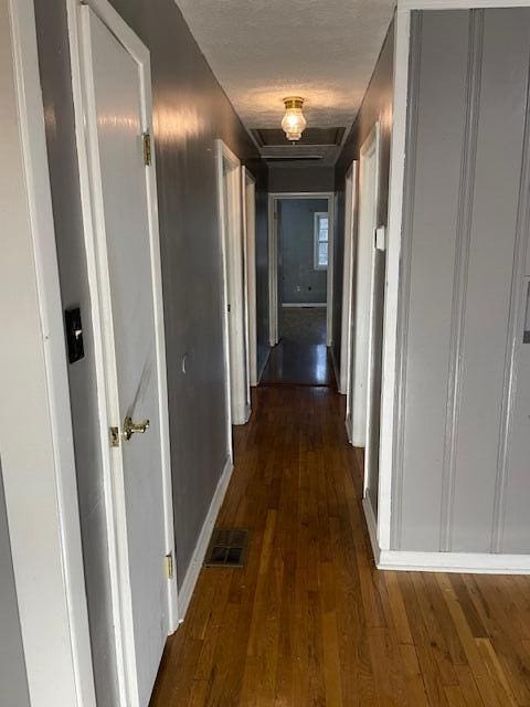 corridor featuring dark wood-type flooring and a textured ceiling