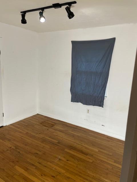 spare room featuring dark wood-type flooring and track lighting