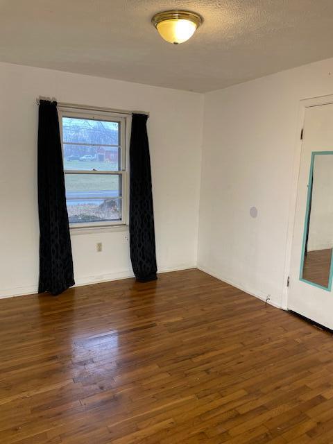 spare room featuring dark hardwood / wood-style flooring and a textured ceiling