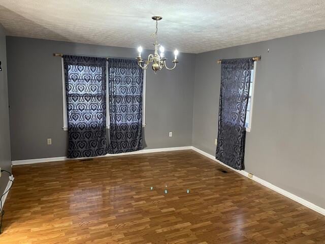 unfurnished room featuring an inviting chandelier, hardwood / wood-style floors, and a textured ceiling