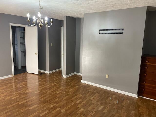 unfurnished dining area with dark hardwood / wood-style flooring, a chandelier, and a textured ceiling