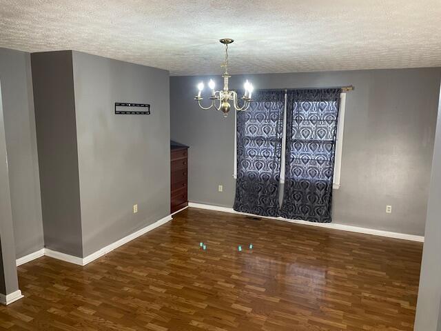 unfurnished dining area with a chandelier, dark hardwood / wood-style floors, and a textured ceiling