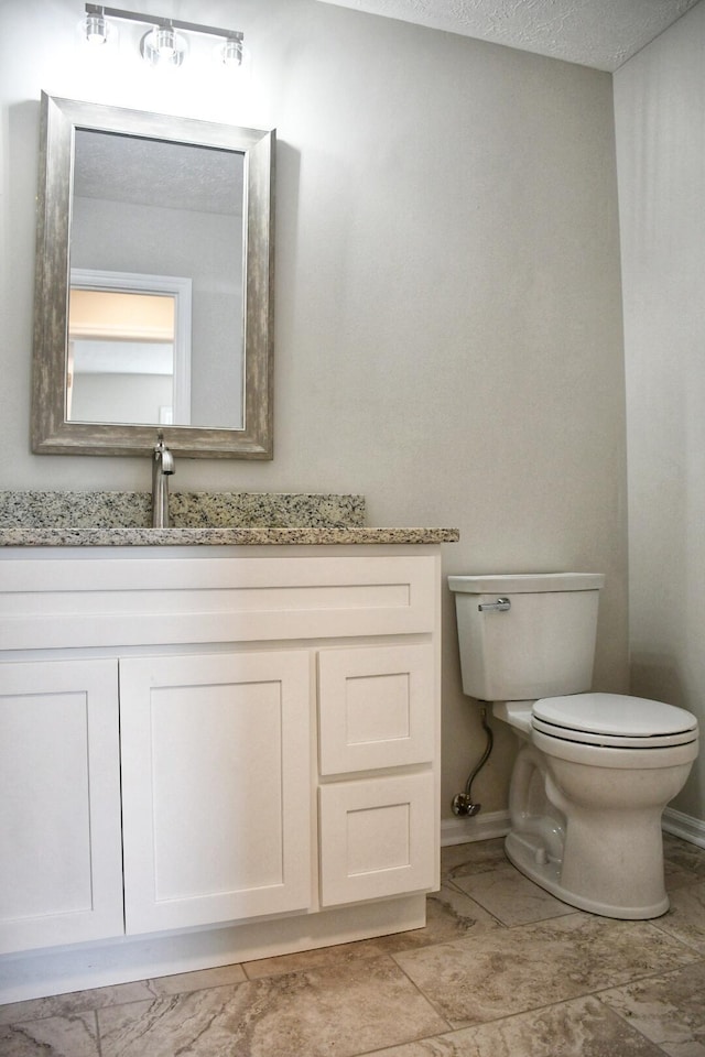 bathroom featuring vanity, toilet, and a textured ceiling