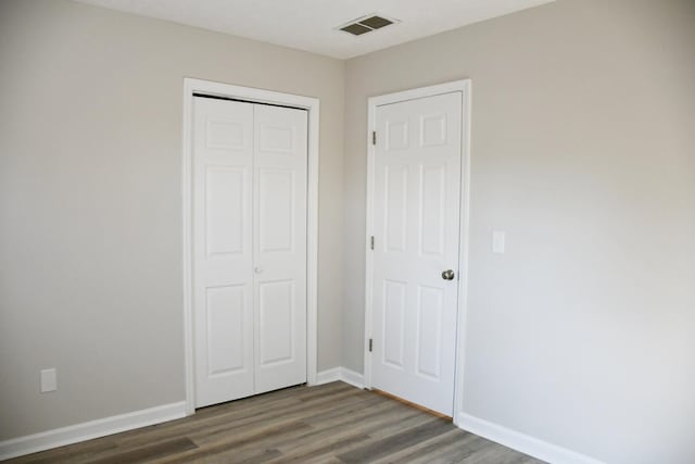 unfurnished bedroom with dark hardwood / wood-style floors and a closet