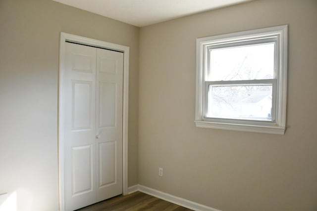 unfurnished bedroom featuring dark wood-type flooring and a closet