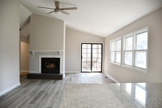 unfurnished living room featuring ceiling fan, vaulted ceiling, and wood-type flooring