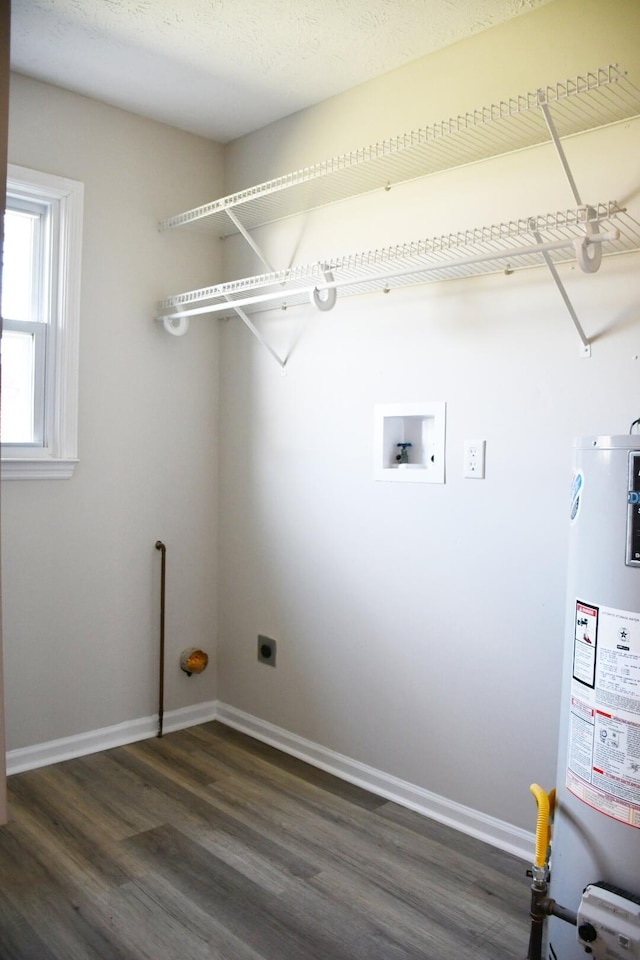 laundry room featuring water heater, electric dryer hookup, dark hardwood / wood-style floors, washer hookup, and a textured ceiling